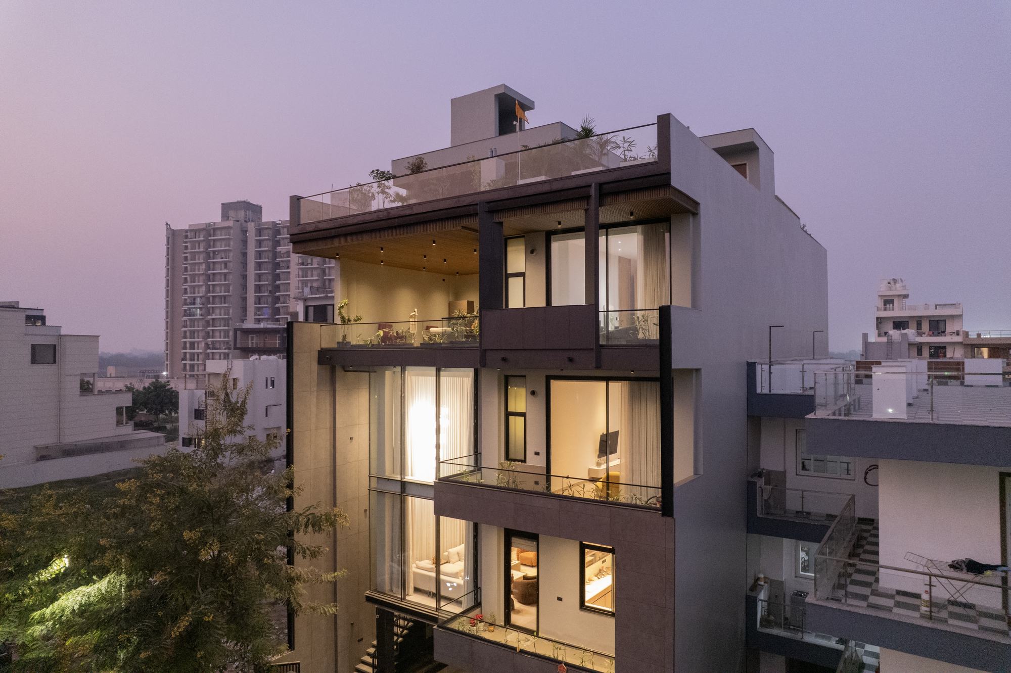 A four-storey home at dusk with its rooms lit from within